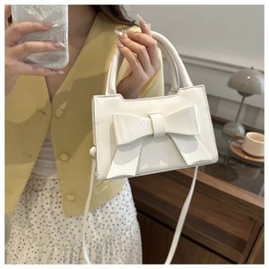 Detailed side view of a white sweet style handbag with large bow and crossbody strap