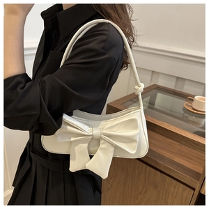 Close-up of white PU leather baguette bag featuring a large bow and slim cord strap