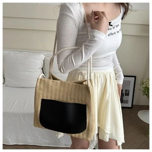 Détail du sac fourre-tout en paille avec poche en cuir noir et anses en corde de coton