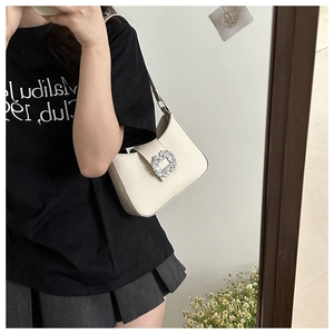Detail of cream white underarm bag featuring a sparkling square rhinestone buckle closure