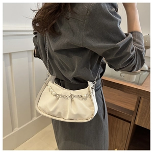 Detail of white pleated crossbody bag with pearl metal chain and faux leather texture
