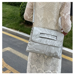Detail of silver textured crossbody bag with unique pleated material and thin shoulder strap