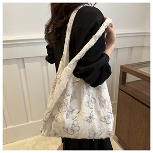 Close-up of white canvas tote bag with blue lace butterfly patterns and textured fabric
