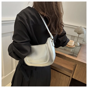 Silver underarm bag with glossy metallic finish shown from a side view on a model