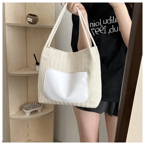 Détail d'un sac cabas tissé beige avec poche en cuir blanc et anses en corde sur modèle