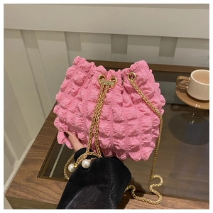 Dettaglio della borsa a secchiello rosa a pieghe con coulisse di perle e catena