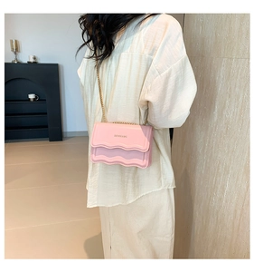 Close-up of pink and lavender patchwork bag with wavy flap texture and gold chain strap