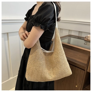 Detail of a large beige straw woven shoulder bag with wide comfortable fabric strap