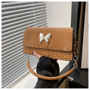 Detail of caramel quilted crossbody bag featuring a silver butterfly metal clasp
