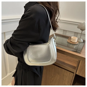Silver metallic crescent hobo bag with a sleek mirror finish shown on shoulder