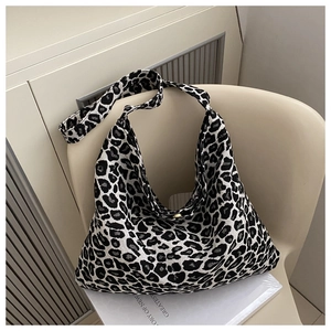 Detail of high-capacity leopard print tote bag with gold snap button and knit texture