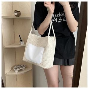 Close-up of beige straw tote bag with white front pocket and minimalist woven texture