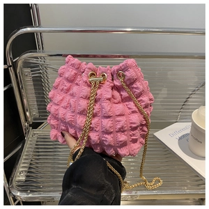 Dettaglio della borsa a secchiello rosa vivace con trama popcorn e catena dorata