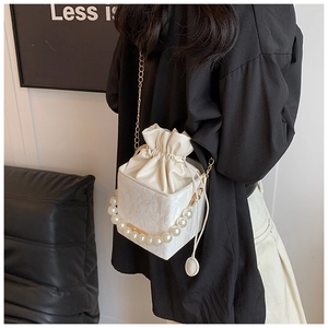 Détail du sac seau en PU crème avec poignée en perles fantaisie et chaîne dorée