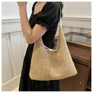 Close-up of beige woven straw shoulder bag with white leather strap on a model