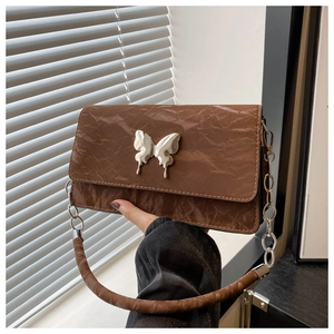 Close-up of brown crinkled patent leather bag with a silver liquid metal butterfly buckle