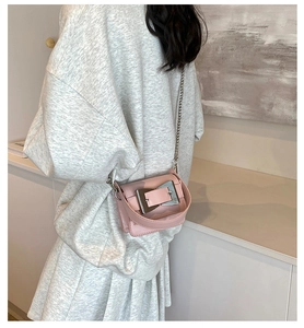Detailed side view of pink crossbody bag with large silver buckle on gray knit outfit