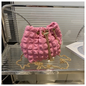 Dettaglio ravvicinato della borsa a secchiello rosa con trama puff e catena dorata