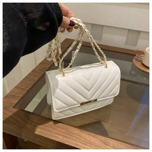 Detail der weißen Stepptasche mit V-Nähten und goldener Kettenriemen-Applikation