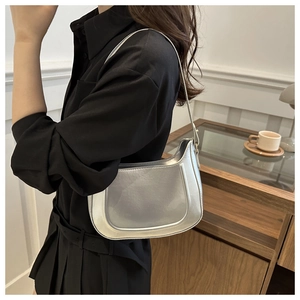 Detail of silver metallic hobo bag worn by model in a warm lifestyle indoor setting