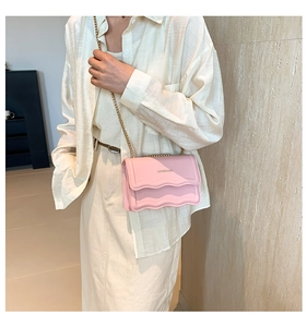 Close-up of pink crossbody bag featuring scalloped flap edges and elegant gold chain strap