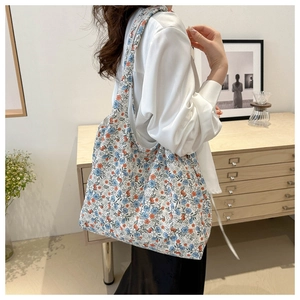 Floral canvas tote bag with blue and orange prints shown on a shoulder in a cozy interior