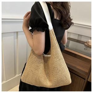 Detail of woven straw shoulder bag featuring beige mesh texture and white leather strap