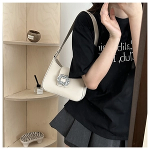 Chic cream leather shoulder bag with crystal buckle shown on a model for style