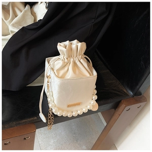 Detail of white PU bucket bag with pleated drawstring and elegant pearl handle