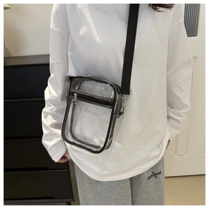 Detail view of transparent PVC crossbody bag with black straps worn on shoulder