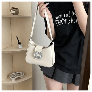 Close-up of minimalist cream underarm bag featuring a luxury rhinestone buckle detail