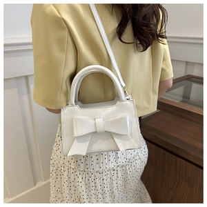 White leather handbag with large bow detail worn by a model in a sweet fashion style