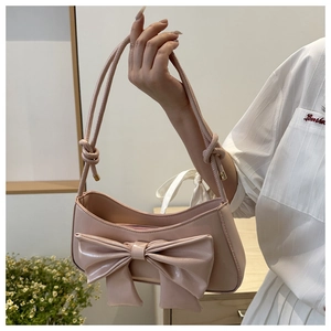 Detail of light pink shoulder bag with large bow and crocodile pattern leather texture