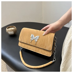 Detail of yellow pleated shoulder bag with oversized silver butterfly metal hardware