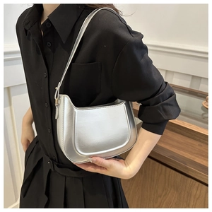 Detail of silver metallic crescent shoulder bag showing glossy texture on black outfit
