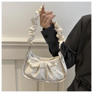 Detail of a creamy white pleated cloud bag with elegant pearl and metal chain strap