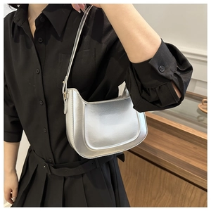 Detail of silver metallic crescent bag with glossy finish on a shoulder-carry model