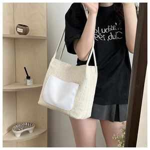 Détail d'un sac cabas tissé beige avec poche extérieure blanche et bandoulières en corde