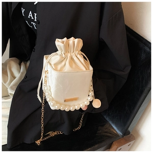 Close-up of white drawstring bucket bag featuring faux leather texture and pearl handle