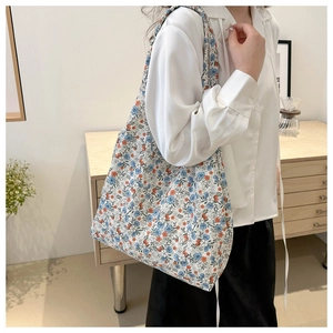 Floral canvas tote bag with blue and orange prints shown in a stylish indoor lifestyle setting