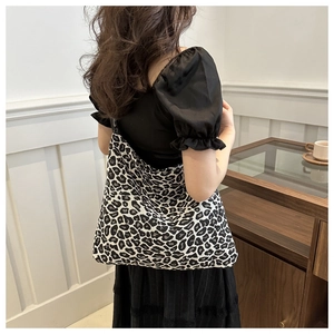 Leopard print nylon tote bag shown on model with black outfit and pleated skirt