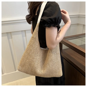 Detail of light beige woven straw tote bag featuring intricate openwork mesh texture