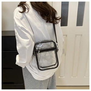 Close-up of clear PVC crossbody bag with adjustable strap worn by a person at home
