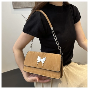 Detail of khaki leather shoulder bag featuring a silver metal butterfly and chain strap