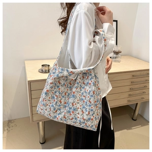 Detail of floral canvas tote bag with blue and orange patterns on a model's shoulder