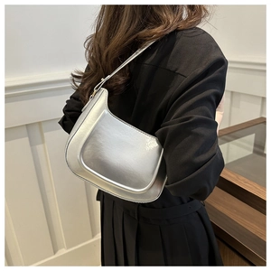 Silver metallic underarm bag on model with adjustable strap and golden hardware accents