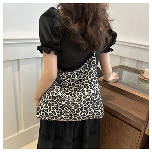 Detail of black and white leopard print nylon tote bag on shoulder in minimalist interior