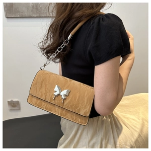 Detail of camel leather crossbody bag with silver butterfly clasp and chain strap