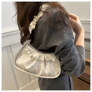 Detailed view of white pleated crossbody bag with pearl chain and satin texture on model
