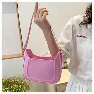 Detailed shot of pink glossy saddle bag featuring embossed lines and smooth leather strap